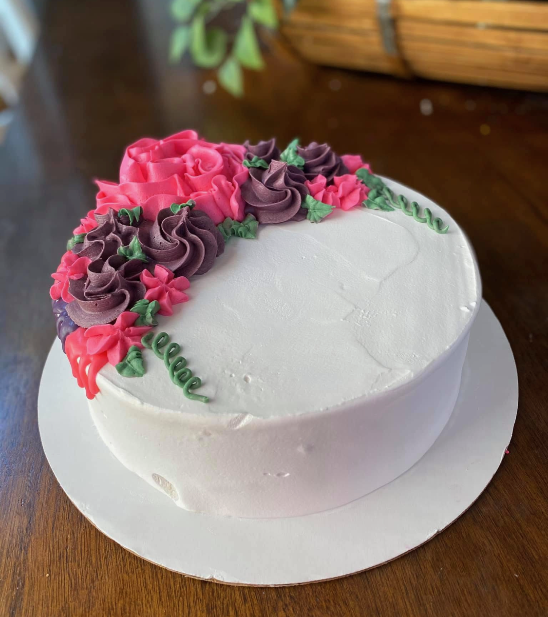 White cake decorated with pink and purple buttercream flowers